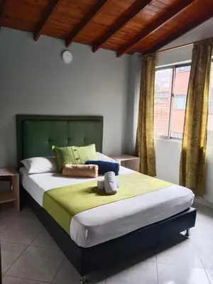 a bedroom with a large bed with a green headboard at Hotel El Deportista in Medellín