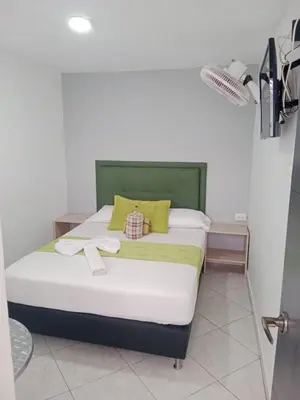 a bed with a green headboard in a room at Hotel El Deportista in Medellín