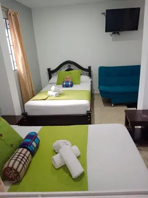a hotel room with two beds and towels on a table at Hotel El Deportista in Medellín