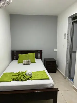 a bedroom with a bed with a green blanket on it at Hotel El Deportista in Medellín