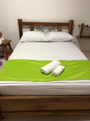 a bed with a green blanket and two towels on it at Hotel San Felipe Belalcazar in Belcazar Caldas