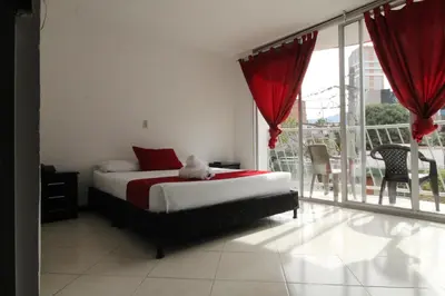 a bedroom with a bed with red curtains and a balcony at Hotel zandalo medellin in Medellín