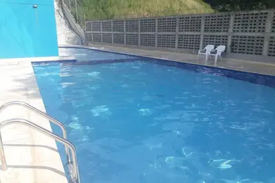 a swimming pool with blue water and two white chairs at Condominio vacacional Paraiso del Sol, San Jeronim in San Jerónimo