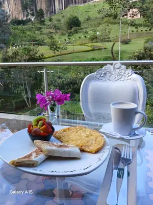 a table with a plate of food and a cup of coffee at Hotel Bahia Del Faro in Guatapé