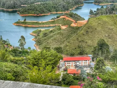 a house on a hill next to a river at Hotel Bahia Del Faro in Guatapé
