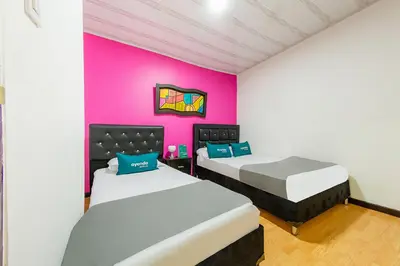 two beds in a room with a pink wall at Ayenda Portal del Cable in Manizales