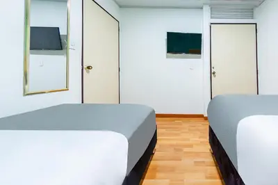 two beds in a room with white walls and wood floors at Ayenda Portal del Cable in Manizales
