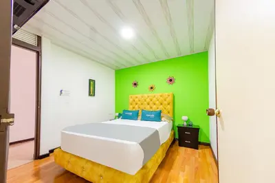a bedroom with a large bed with a green wall at Ayenda Portal del Cable in Manizales