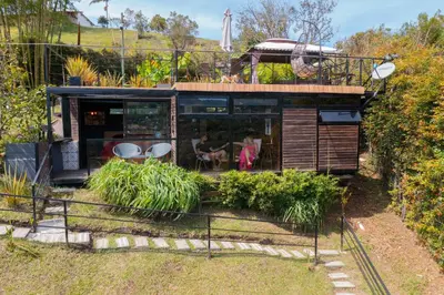 a tiny house with a restaurant on a hill at Glamping Montecarlo Lodge Cubo de Madera-Guatapé in Guatapé