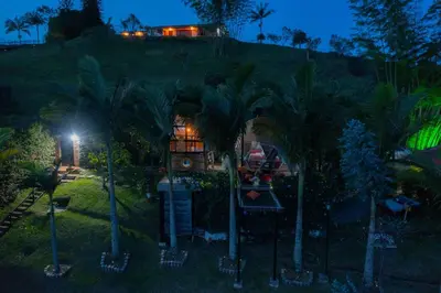 a house on a hill with palm trees at night at Glamping Montecarlo Domo Geodesico y Sauna Finlandés Guatapé in Guatapé