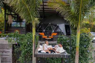 a man and woman sitting on a bench under a tent at Glamping Montecarlo Domo Geodesico y Sauna Finlandés Guatapé in Guatapé