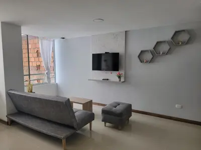 a living room with a chair and a tv on a wall at Apartamento FL Martinz in Manizales