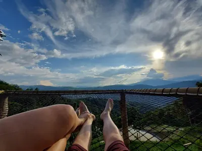 a woman with her feet up on a fence looking at the water at Entre Verdes Hotel & Glamping in Medellín