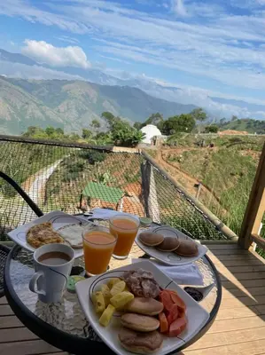 a breakfast table with a plate of food and orange juice at Entre Verdes Hotel & Glamping in Medellín