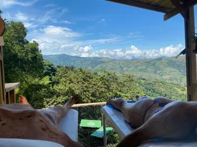 two people laying on a balcony looking out at the mountains at Entre Verdes Hotel & Glamping in Medellín