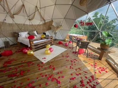 a room with a bed and red flowers on the floor at Entre Verdes Hotel & Glamping in Medellín