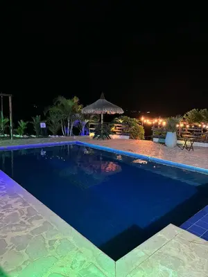 a swimming pool at night with a table and umbrella at Entre Verdes Hotel & Glamping in Medellín