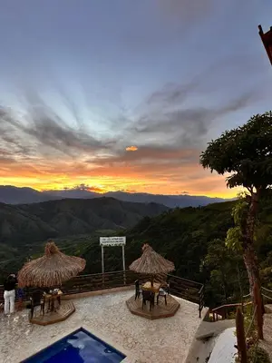 a view of a sunset from a resort with tables and umbrellas at Entre Verdes Hotel & Glamping in Medellín