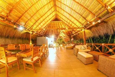 a large room with a table and chairs and a straw roof at Refugio Monte Oscuro in Las Mercedes