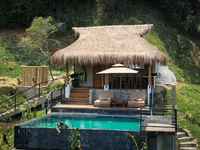 a hut with a pool and chairs and a thatch roof at Refugio Monte Oscuro in Las Mercedes