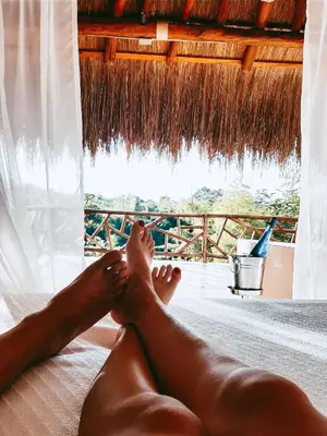 a person laying on a bed with their feet on a window at Refugio Monte Oscuro in Las Mercedes