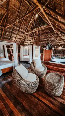 a room with two beds and wicker chairs at Refugio Monte Oscuro in Las Mercedes