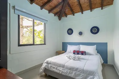 a bedroom with a large white bed with a window at Soy Local Guatape Campestre in Guatapé
