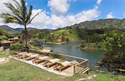 a group of lounge chairs and a river with mountains at Soy Local Guatape Campestre in Guatapé