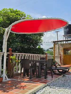 a table and chairs under a red umbrella on a patio at La mejor opción para tu descanso y recreación. in Mariquita
