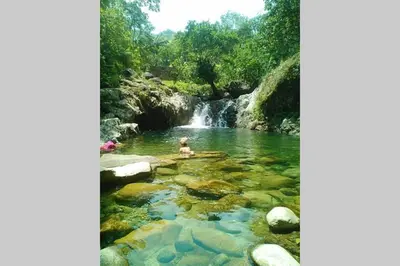 a person swimming in a river with a waterfall at Hermoso y cómodo apartamento in San Rafael