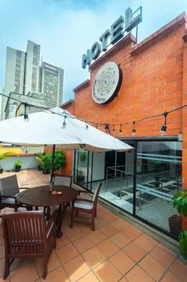 a table and chairs with an umbrella in front of a building at Mandala Medellin Botero By GyC Hotels in Medellín