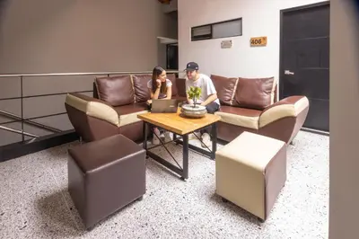 a man and a woman sitting on a couch with a laptop at Mandala Medellin Botero By GyC Hotels in Medellín
