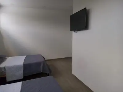 a room with two beds and a flat screen tv at Hotel HACIENDA SAN AGUSTIN in Marinilla