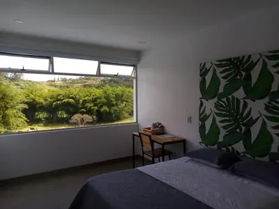 a bedroom with a bed and a large window at Hotel HACIENDA SAN AGUSTIN in Marinilla