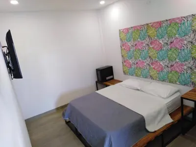 a bedroom with a bed with a painting on the wall at Hotel HACIENDA SAN AGUSTIN in Marinilla