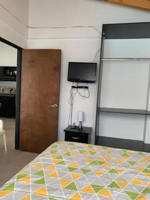 a bedroom with a bed and a tv and a door at Apartamento La Esperanza Guatapé in Guatapé