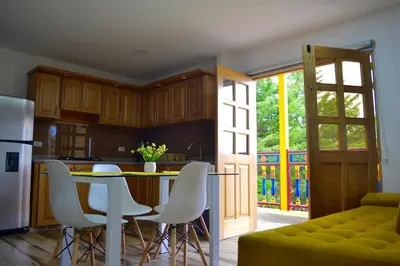 a kitchen with a table and some white chairs at Roble Colonial - Apartamentos Deluxe en Guatapé in Guatapé