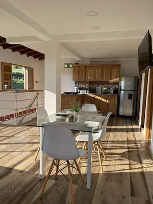 a kitchen with a glass table and white chairs at Roble Colonial - Apartamentos Deluxe en Guatapé in Guatapé
