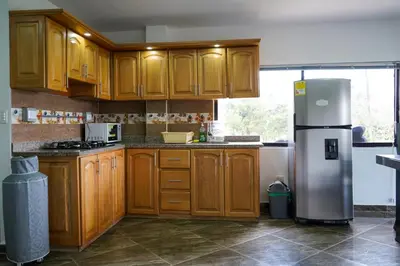 a kitchen with wooden cabinets and a stainless steel refrigerator at Roble Colonial - Apartamentos Deluxe en Guatapé in Guatapé