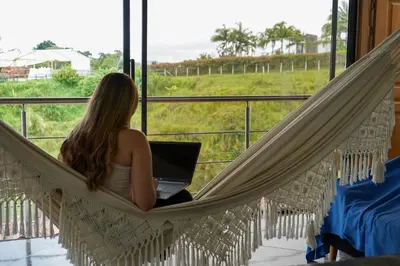 a woman sitting in a hammock with a laptop at Roble Colonial - Apartamentos Deluxe en Guatapé in Guatapé