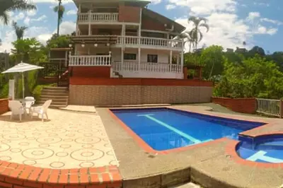 a house with a swimming pool in front of a house at Apartamento campestre in Manizales