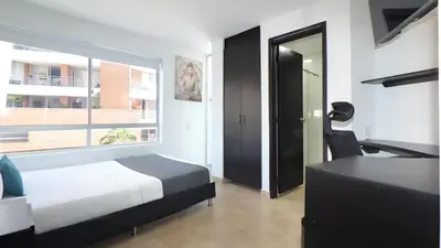 a bedroom with a bed and a desk and a window at Ayenda Coliving la 78A in Medellín