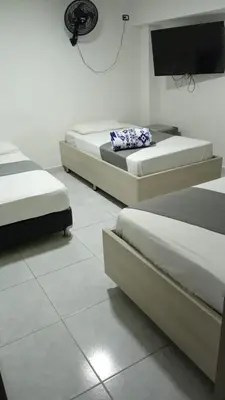 a room with three beds and a flat screen tv at Hotel Urbano 70 in Medellín