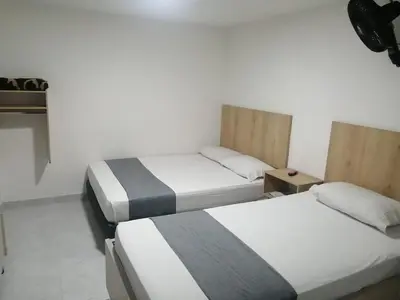 two beds in a room with white walls at Hotel Urbano 70 in Medellín