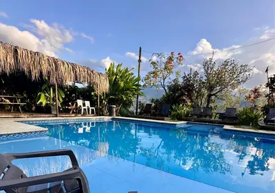 a large blue swimming pool with chairs and trees at Finca Hotel Tierra Verde in Girardota