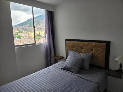 a bedroom with a bed with a large window at Apartamento vistas lindas cerca centro in Medellín
