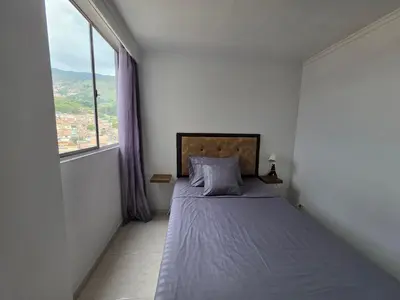 a bedroom with a bed and a large window at Apartamento vistas lindas cerca centro in Medellín