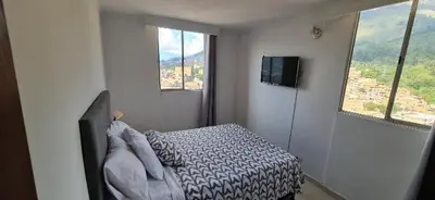 a bedroom with a bed and two windows and a television at Apartamento vistas lindas cerca centro in Medellín