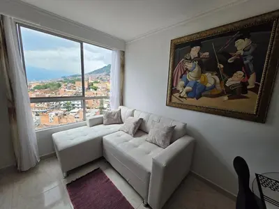 a living room with a white couch and a large window at Apartamento vistas lindas cerca centro in Medellín