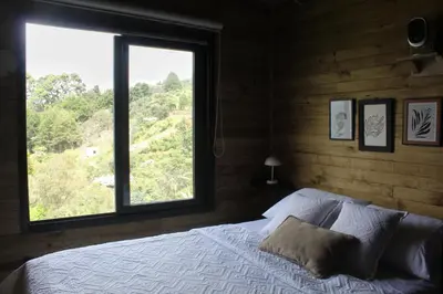 a bedroom with a bed with a large window at Glamping con jacuzzi cerca a Medellin in Guarne